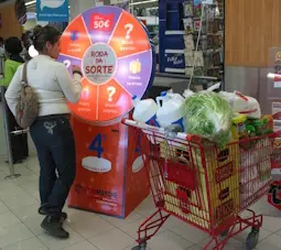 Uma consumidora no supermercado com o carrinho cheio de compras, participa na Roda da Sorte Amazing!